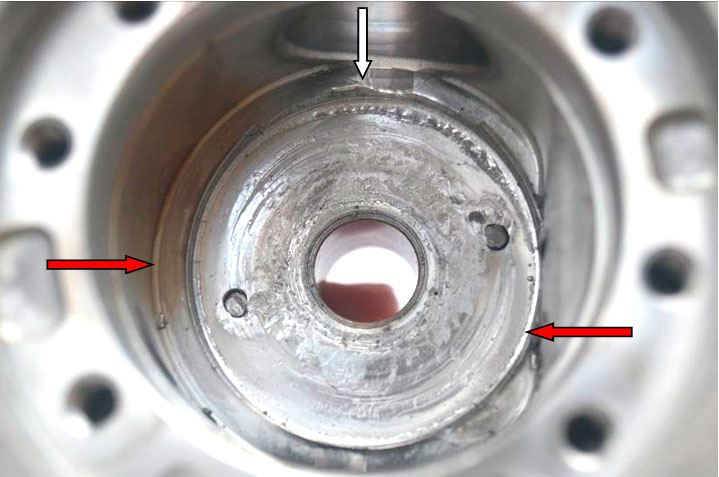 Фото 32. Повреждения корпуса в виде задиров за задней опорной шайбой. Металлический буртик показан красными стрелками, а место его повреждения белой стрелкой.